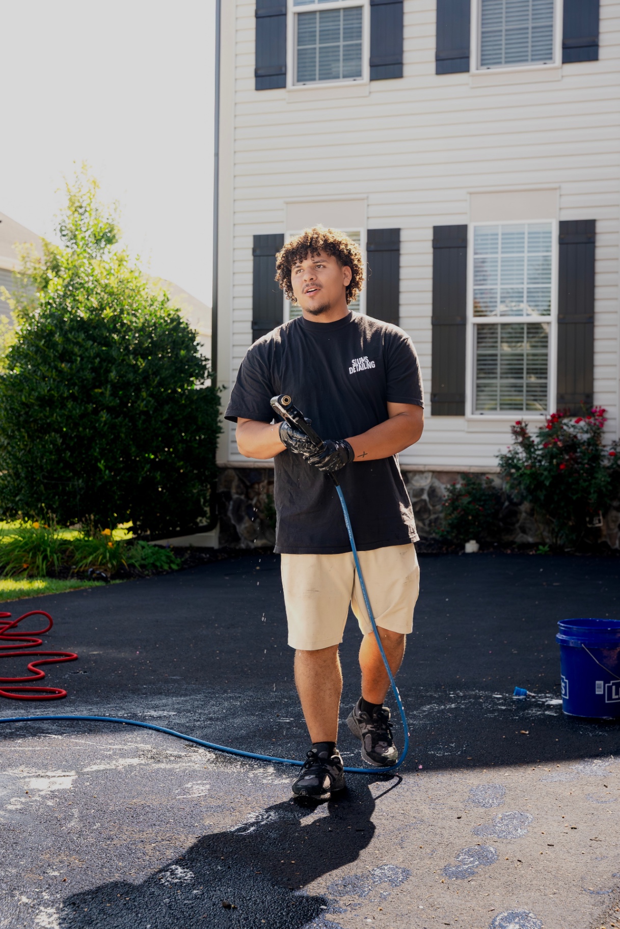 Dominick, owner of Slums Mobile Detailing, working the rinse hose in a customer's driveway in Hagerstown, MD