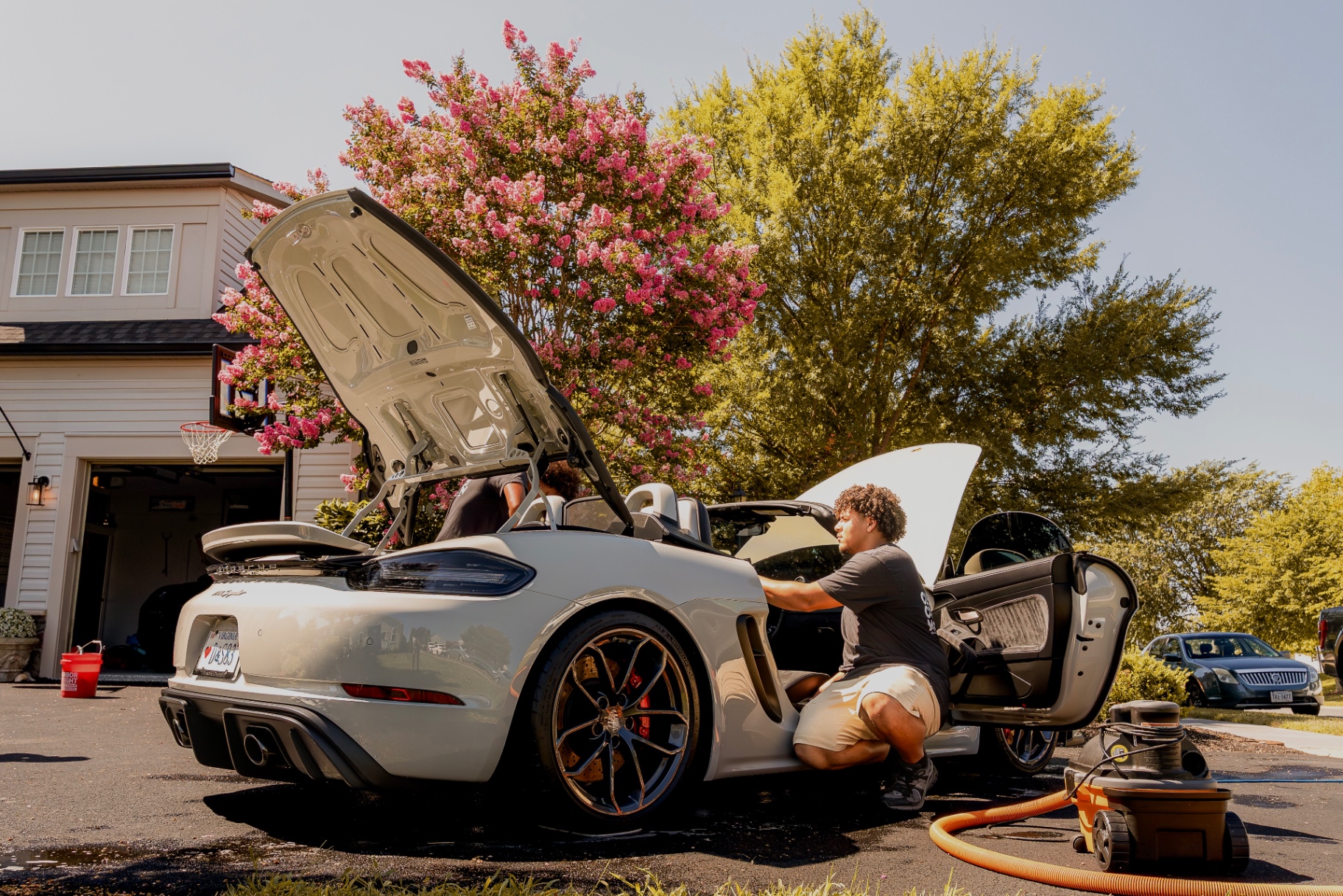 Full detail in progress — doors, hood and trunk open on a Porsche Boxster with the vacuum running